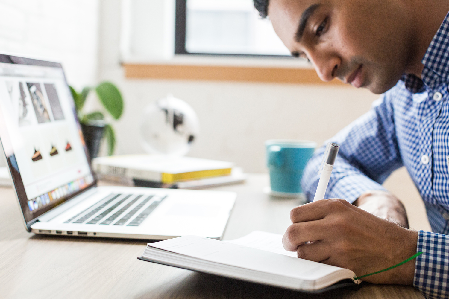 young man working on laptop and taking notes