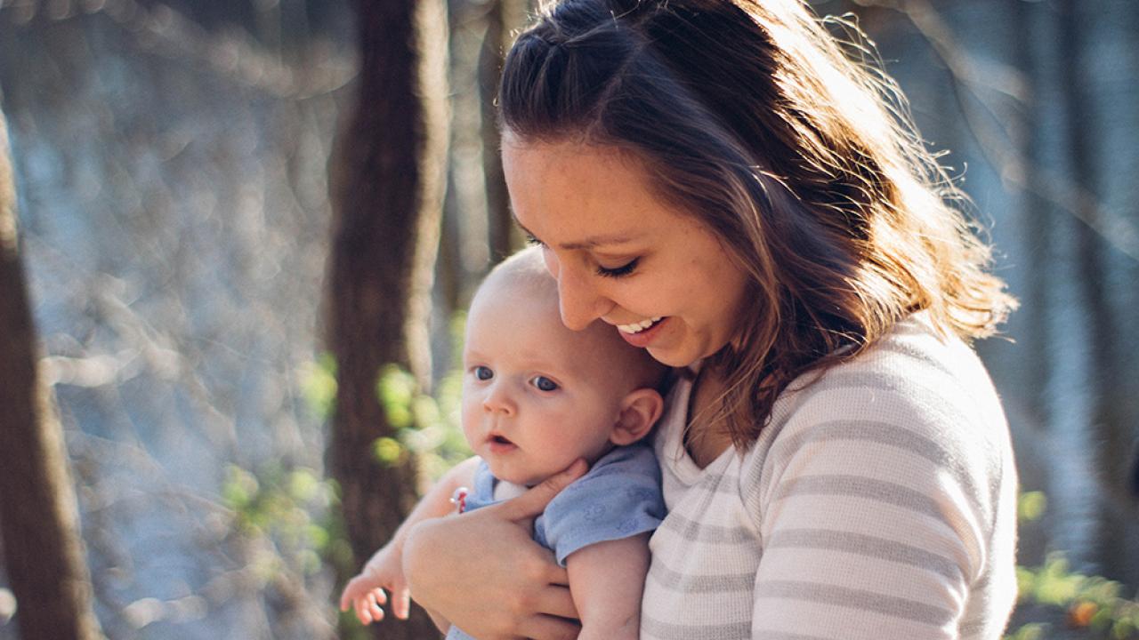 young mother smiling and holding her newborn child