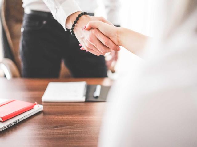 man and woman shaking hands over a desk