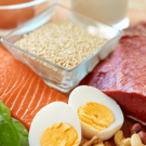 Assorted fresh ingredients including salmon, beef, chicken, eggs, nuts, and herbs.