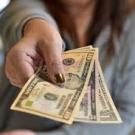 Close-up of a woman's hand offering US dollar bills